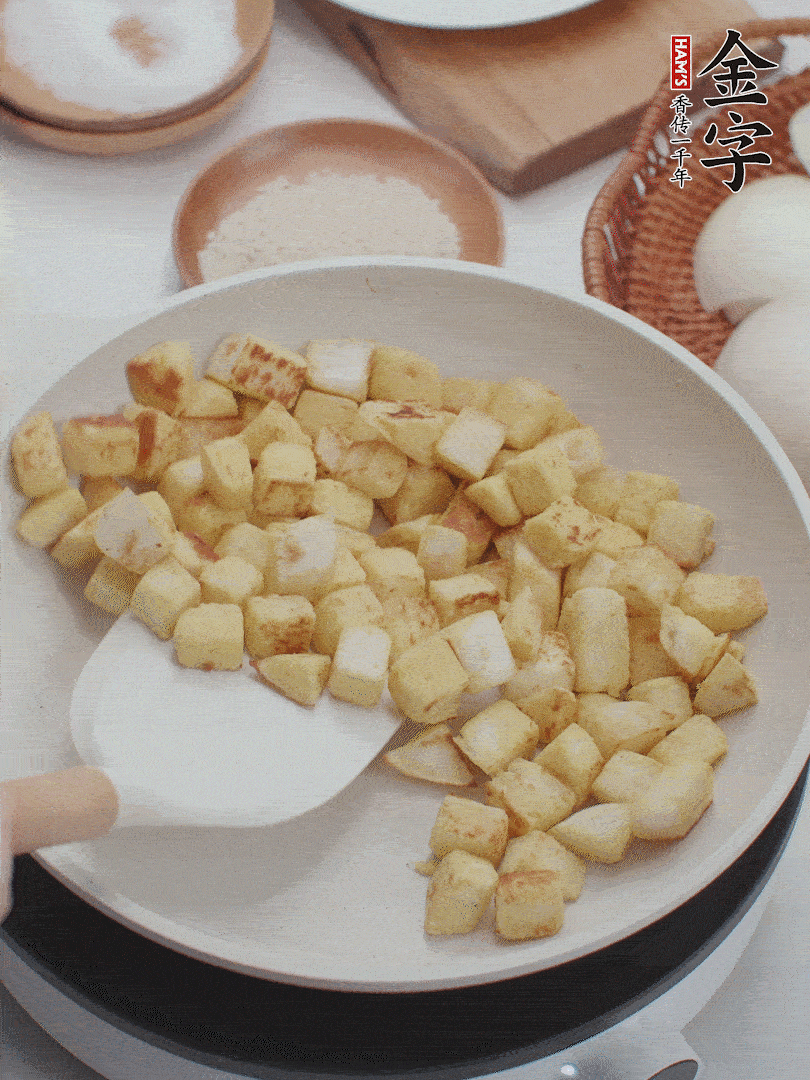 起鍋熱油，倒入饅頭丁，小火煎至蛋液凝固定型再翻面，饅頭丁部煎至金黃時(shí)盛起待用。